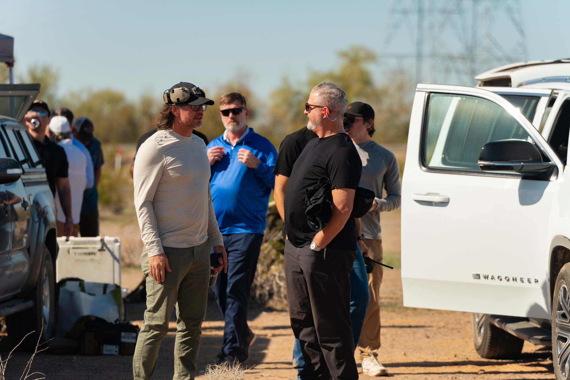 Attendees talking beside vehicles in the desert